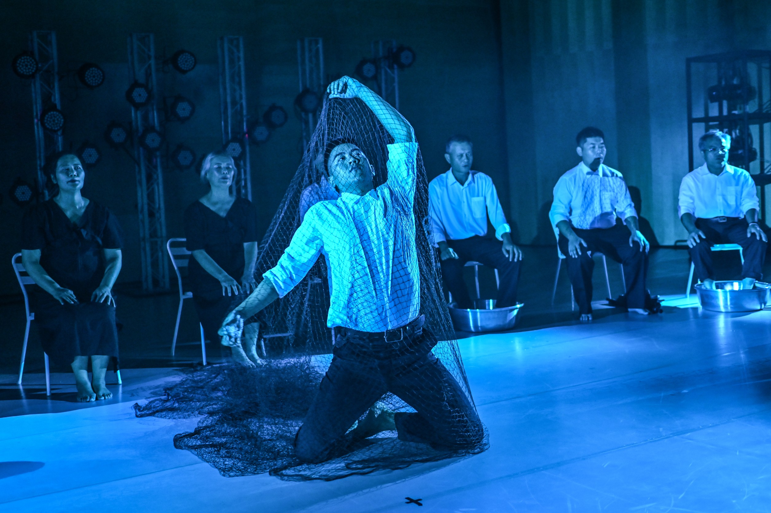 聽海的呢喃劇照，飾演船員的男子，被魚網密密纏繞，掙脫不開，表達海上生活的煎熬苦悶。杵音文化藝術團提供。