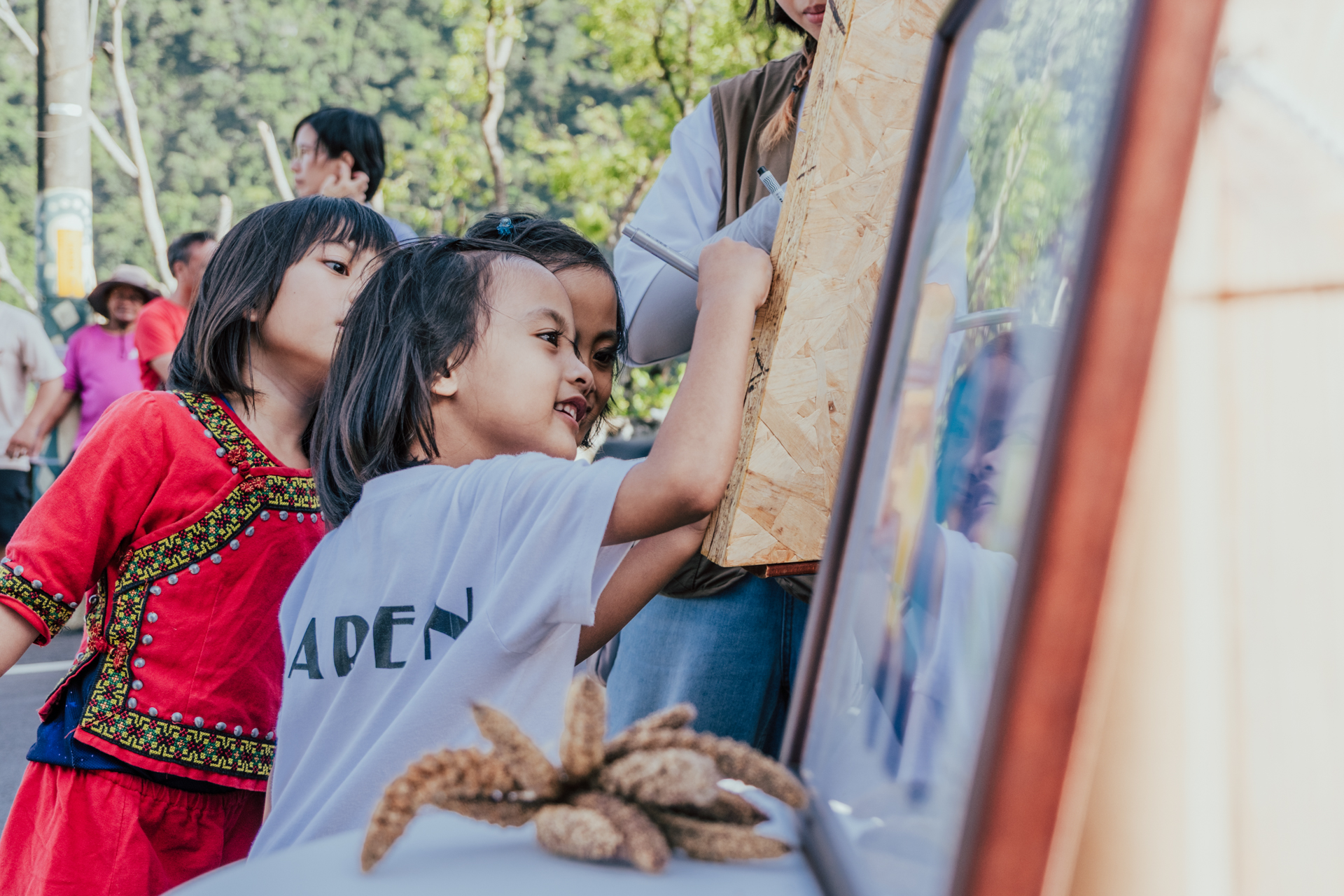 大家輪流在木牌上留下名字，孩子踮著腳努力寫下自己的痕跡。