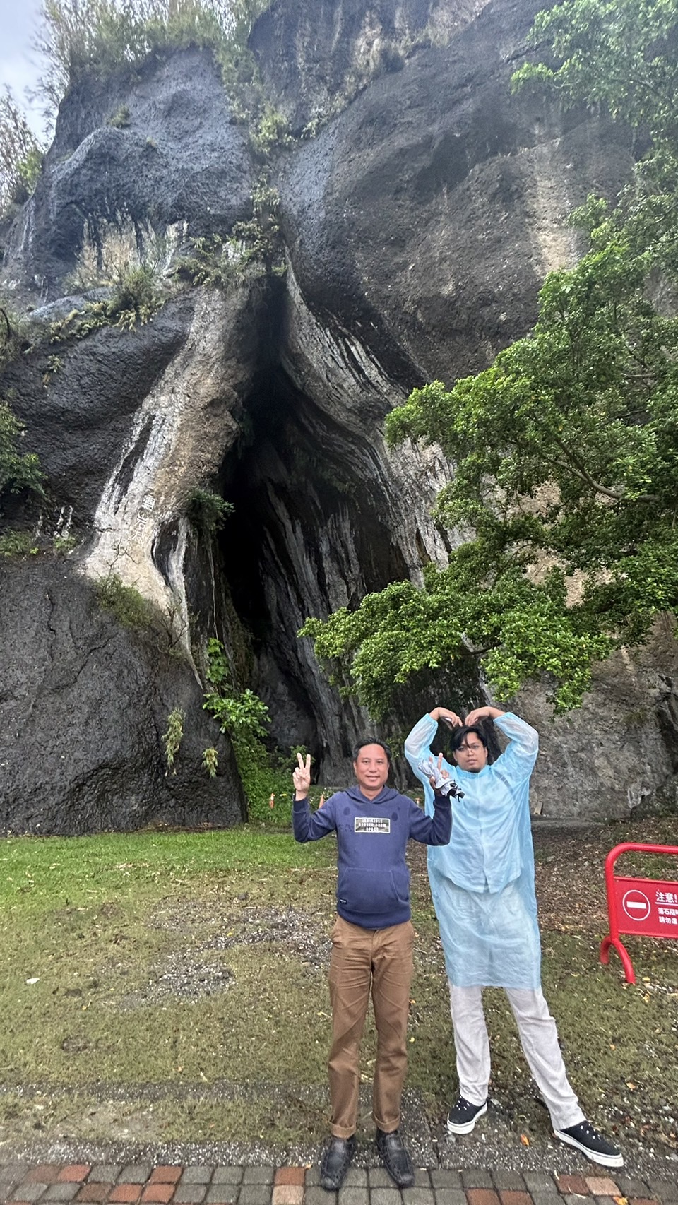 Najmie and Razif from Sabah, Malaysia, enjoy themselves in front of Baxian Cave in the rain. (Photo by Lin Sung-En)